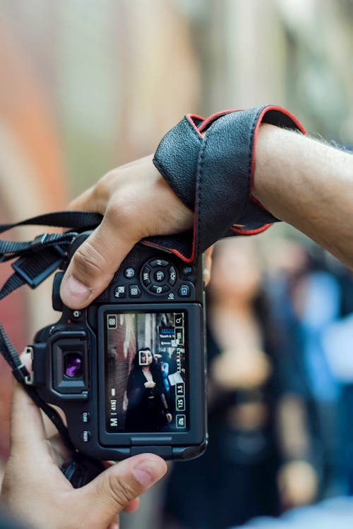 Man Hands Holding Camera and Taking Pictures of Woman