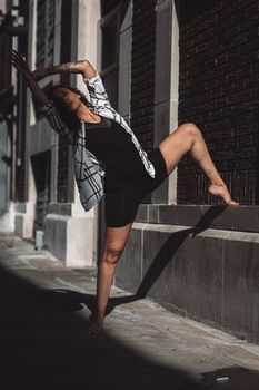 A woman performs an elegant dance pose in the urban streets of Orlando, FL.