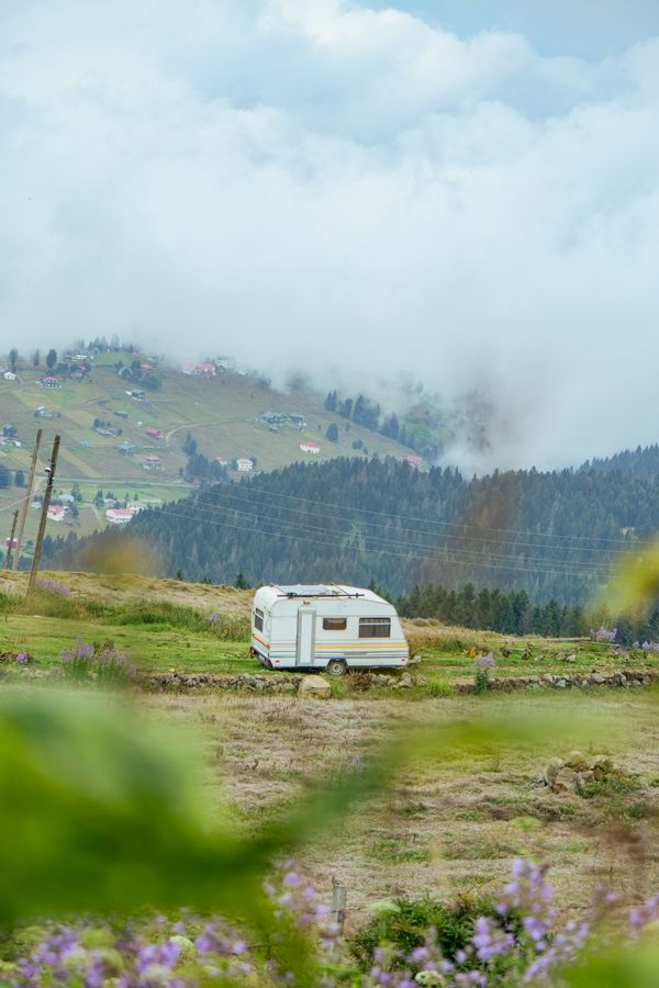 Touring caravan standing on open grassland with misty rolling hills and cloud behind