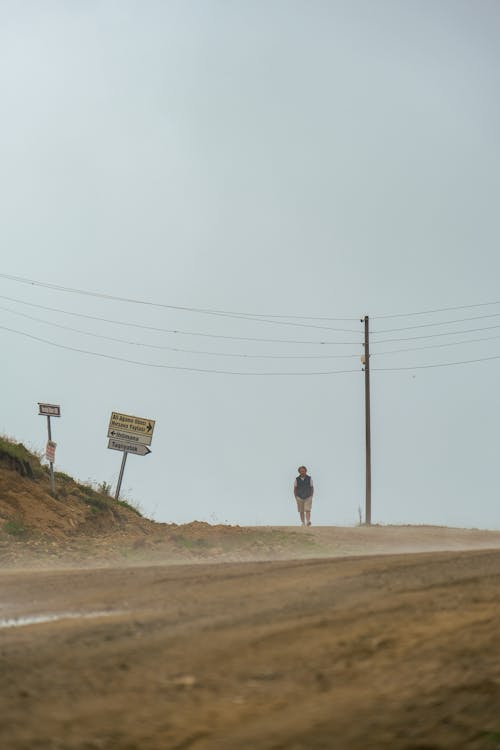 Person Walking on Brown Dirt Road