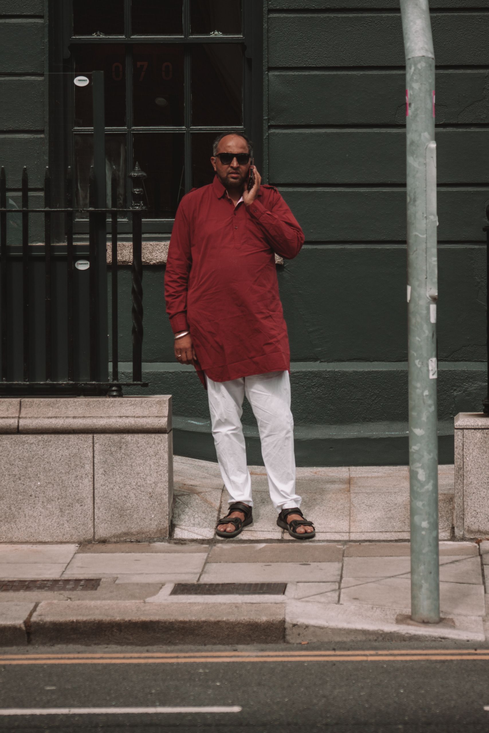 Man Wearing a Red Shirt and Sunglasses Standing on a Street by a Dark ...