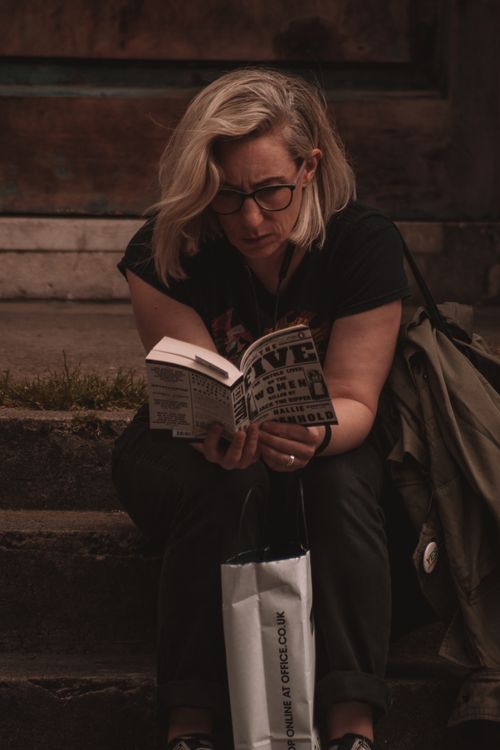 Free A woman with blonde hair engrossed in reading a book on steps in Dublin, Ireland. Stock Photo