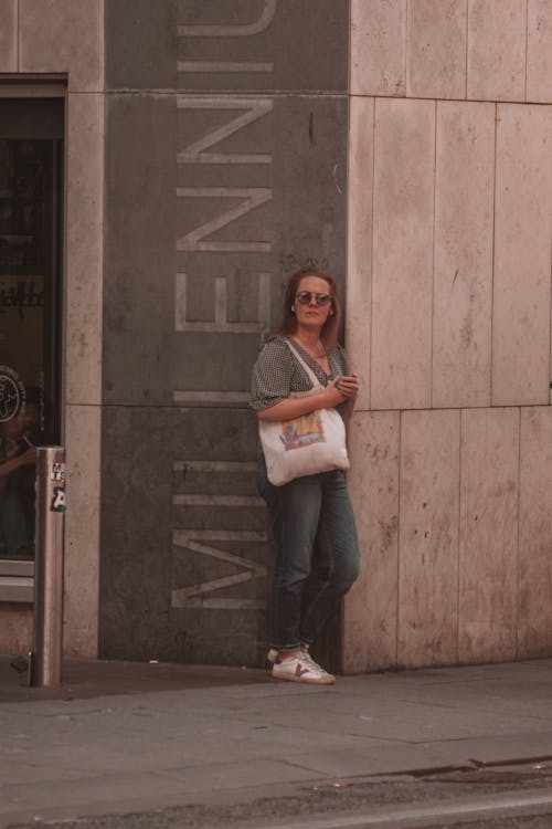 Woman Leaning Against a Building Facade in City 