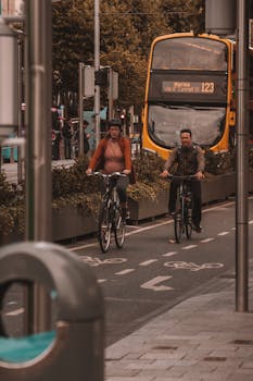 Two cyclists ride in a designated bike lane in Dublin with a city bus in the background.
