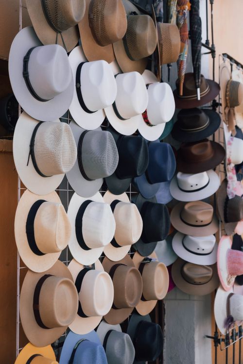 Free A variety of fashionable hats showcased on a street vendor's rack, perfect for style enthusiasts. Stock Photo