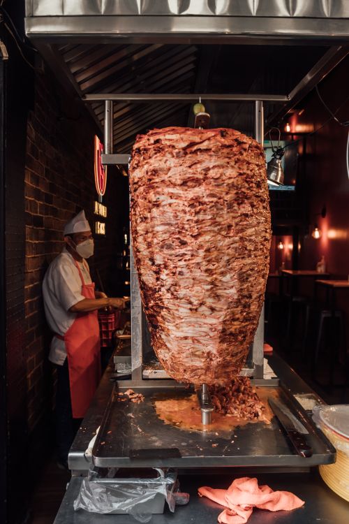 Free Deliciously stacked shawarma meat on rotating spit in a bustling Ciudad de México eatery. Stock Photo