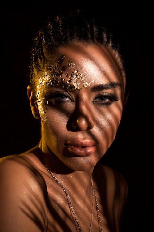 Portrait of a Woman in Creative Gold Makeup with Shadows on Her Face 