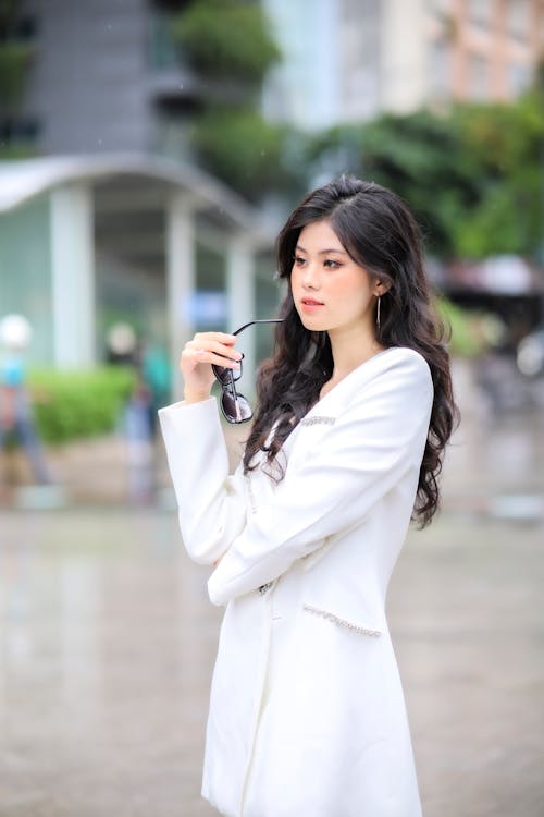 Beautiful Woman Holding Sunglasses While Looking Away