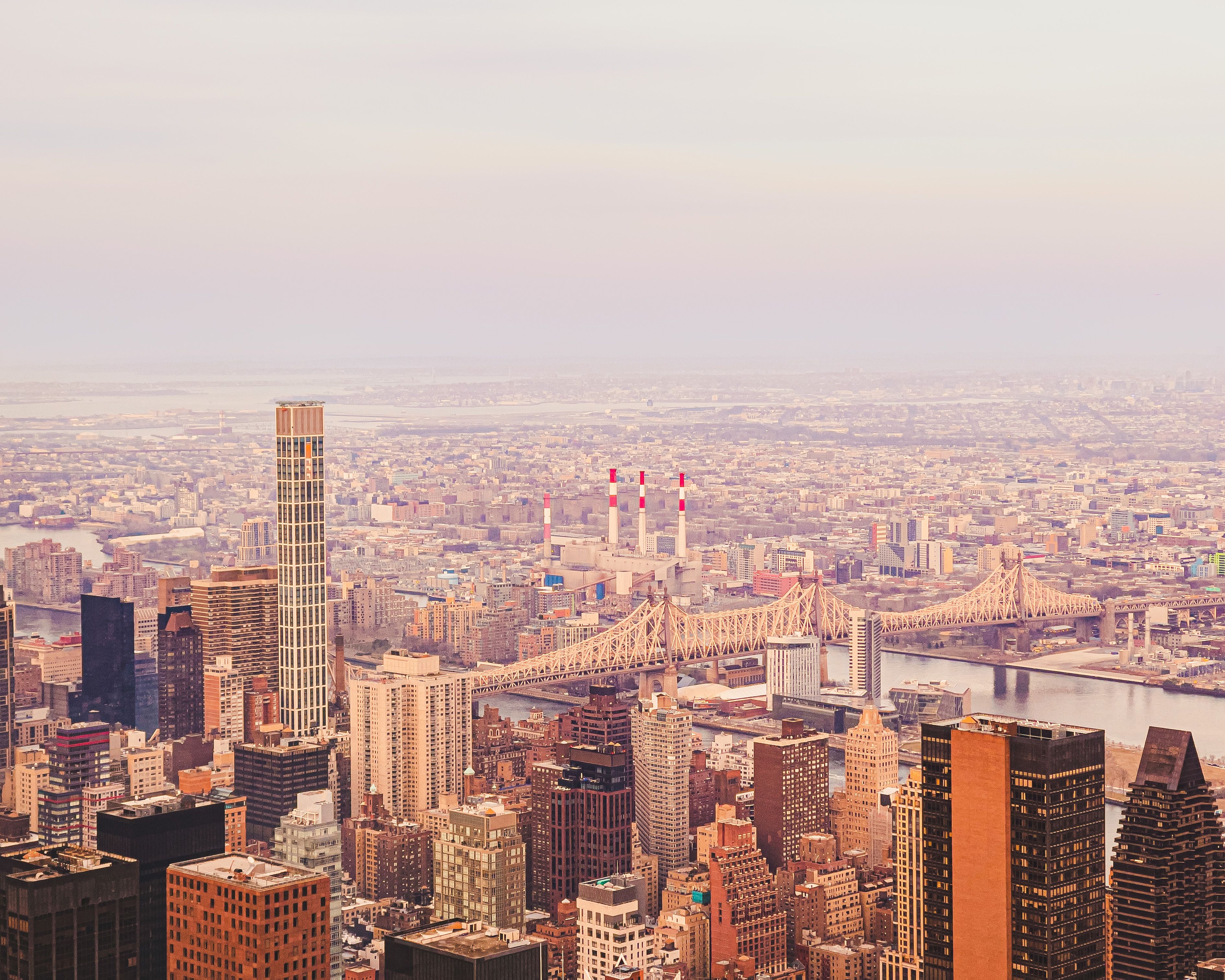 NY Helicopter Tour: Manhattan Highlights - A breathtaking aerial view of New York City with the iconic Queensboro Bridge and Manhattan skyline at sunset.