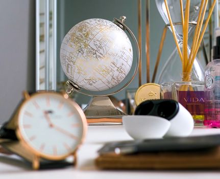 A stylish desk arrangement featuring a globe, clock, and various decorative items in a modern setting.