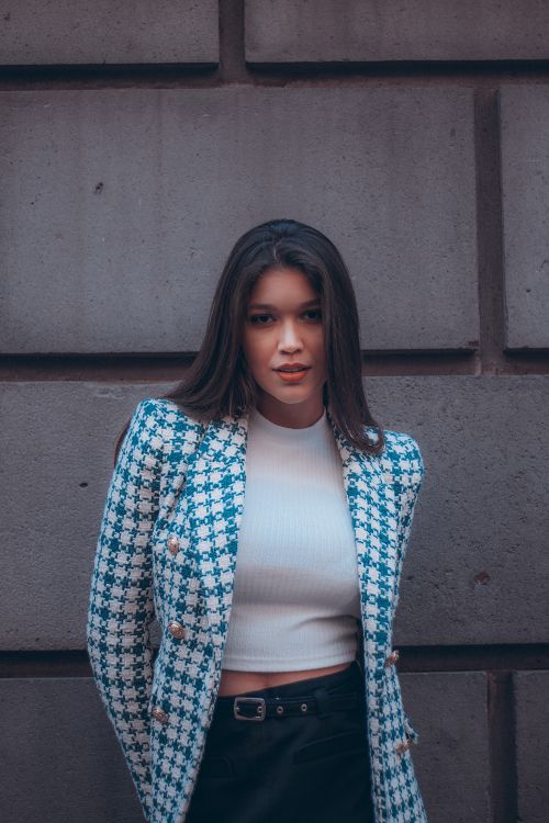 Free Fashionable woman in a blue jacket poses confidently by a concrete wall. Stock Photo