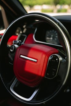 Close-up of a luxury car interior featuring a red steering wheel and dashboard.