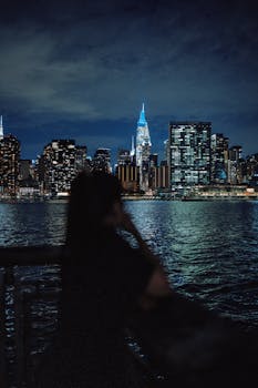 Silhouette of a person viewing the illuminated city skyline at night.