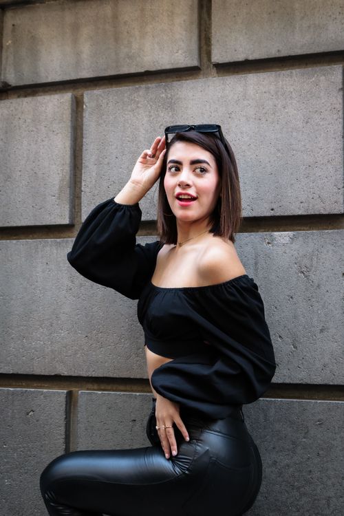 Free Confident woman in black outfit posing against a gray urban wall, showcasing fashion elegance. Stock Photo