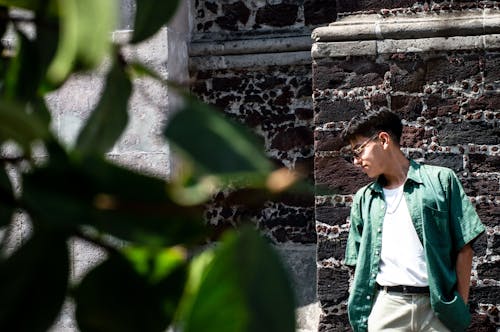 Young Man with a Hands in Pockets Leaning against a Building