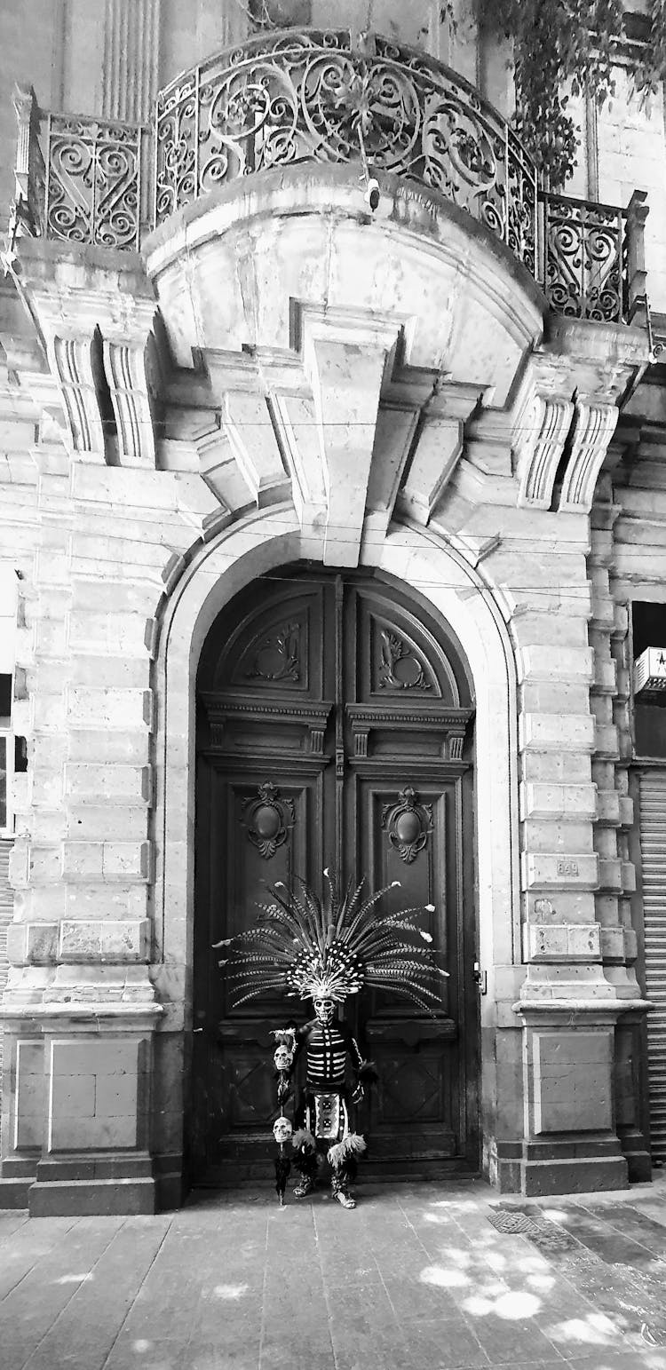 Man In Costume For Dia De Muertos Posing By Building Door