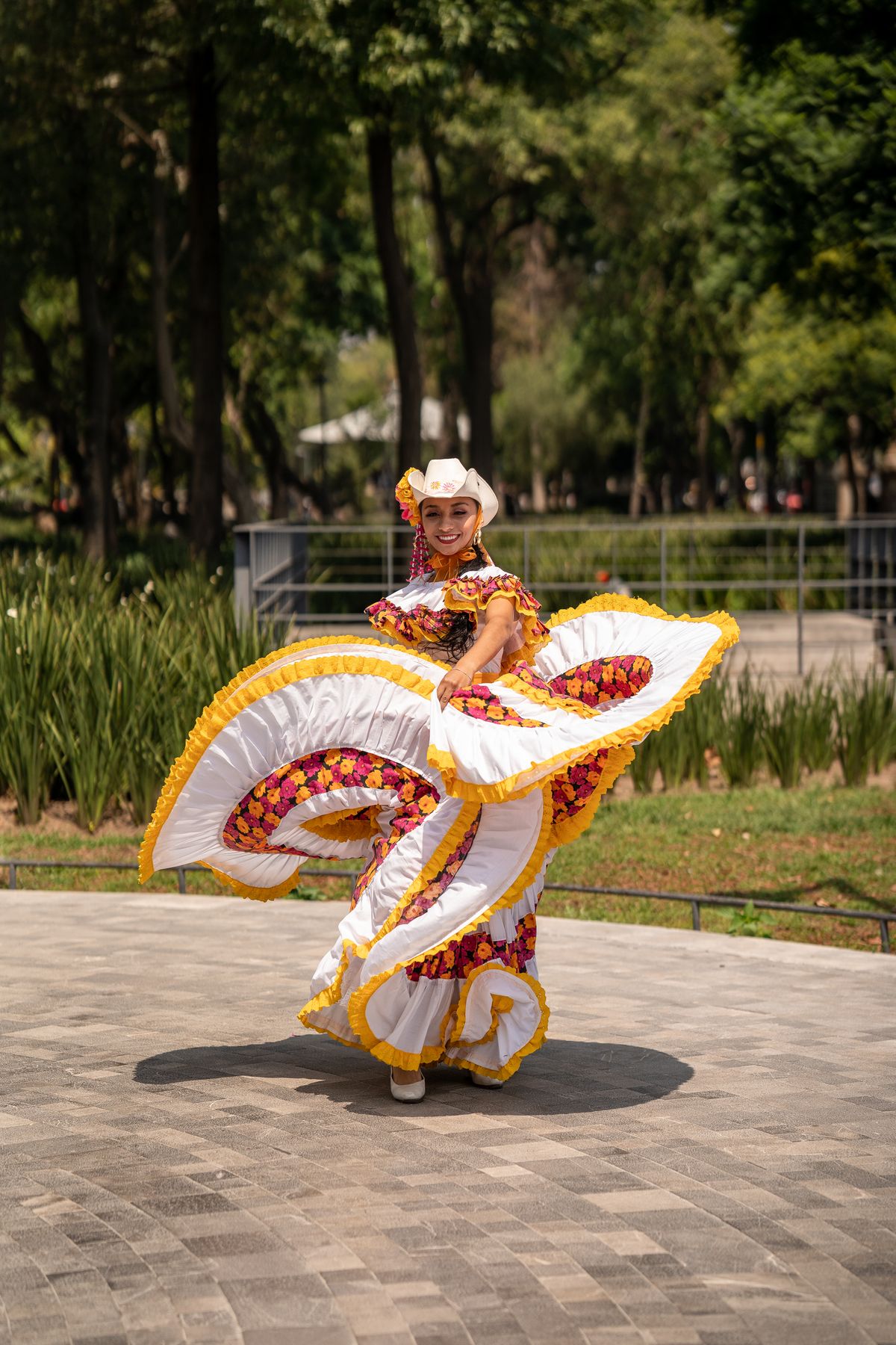 Traditional Mexican folklorico dancer in vibrant dress performing in a Mexico City park.