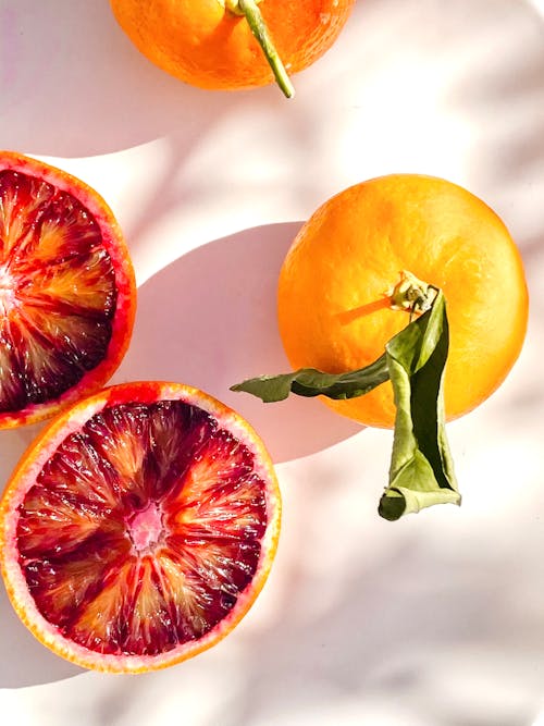 Oranges and Sliced Grapefruit on White Surface