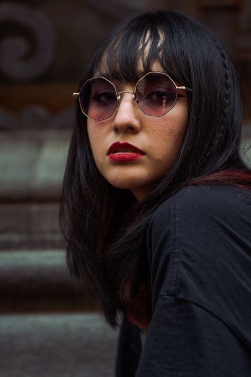 Free Portrait of a fashionable woman with sunglasses, bold lipstick, and dark hair outdoors. Stock Photo
