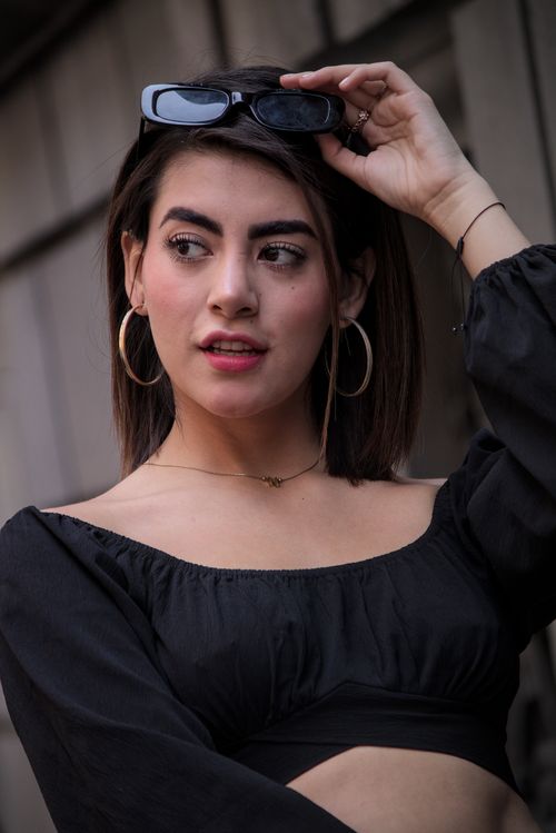 Free Portrait of a fashionable young woman wearing hoop earrings and sunglasses outdoors. Stock Photo
