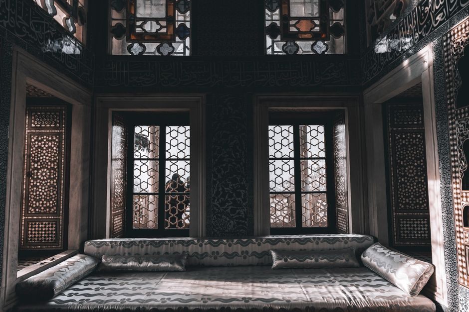 Quiet Luxury decor style interior — Sunlight streams through ornate windows onto a luxurious couch, creating a serene ambiance in this Middle Eastern interior.