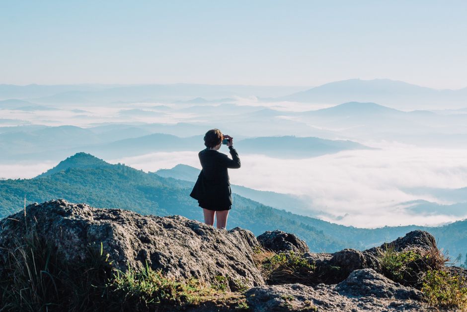 A woman enjoys a panoramic mountain view with binoculars, capturing the adventurous essence of nature.