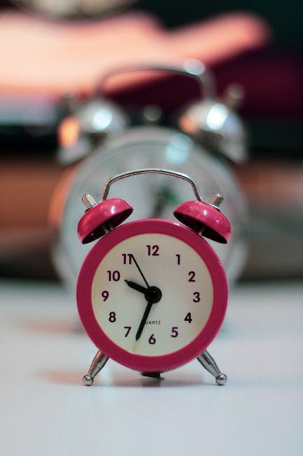 Pink analogue alarm clock with blurred background, perfect for time or design concepts.