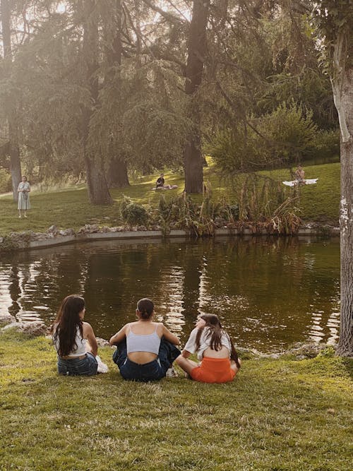 Women Sitting on the Grass Near the Lake 