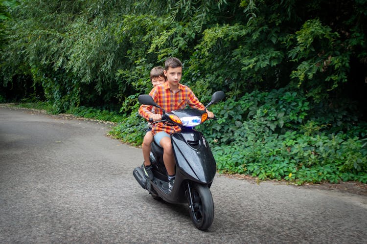 Young Boys Riding On A Scooter 