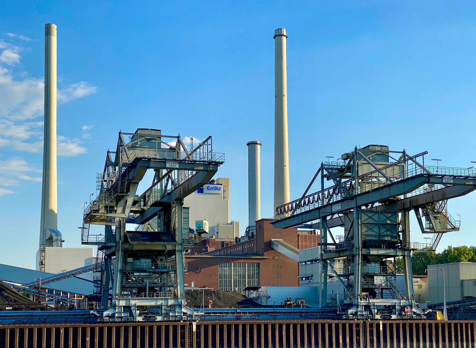 Industrial facility in Karlsruhe, Germany, featuring tall chimneys and blue sky.
