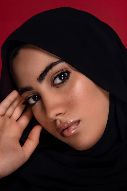 Free A close-up portrait of a beautiful woman in a hijab against a striking red background, showcasing elegance. Stock Photo