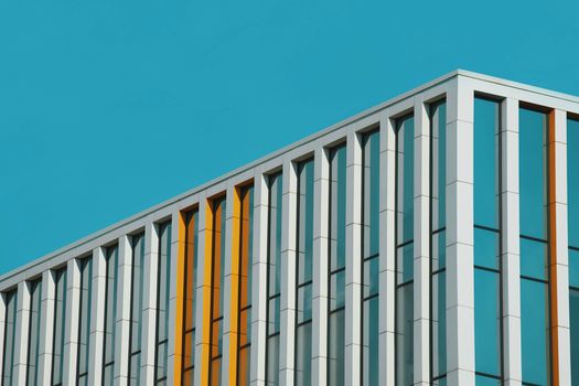 Sleek modern building facade featuring geometric lines and glass panels against a blue sky.