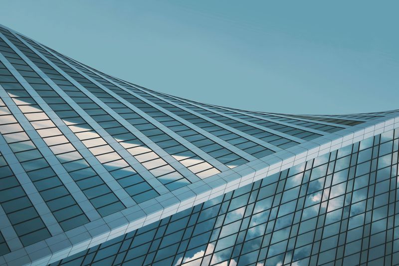 Curved glass roof structure glowing against a teal sky