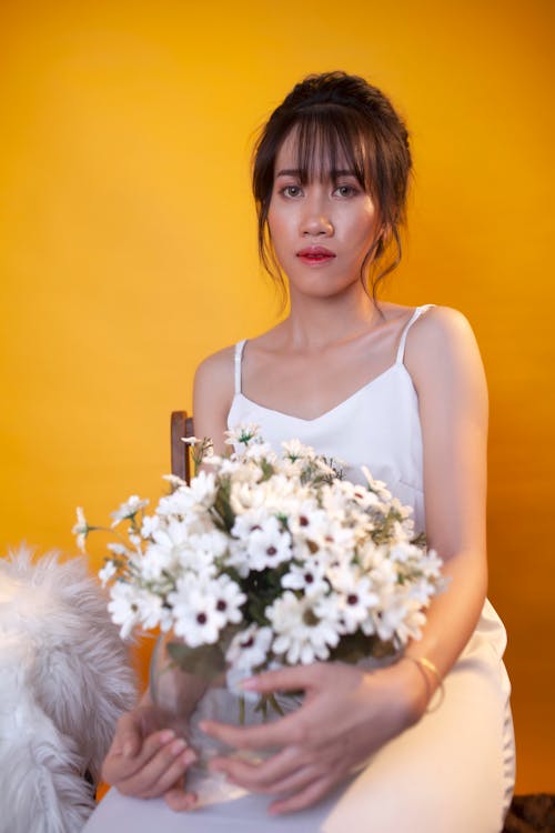 White Flowers held by a Beautiful Woman in White Dress 