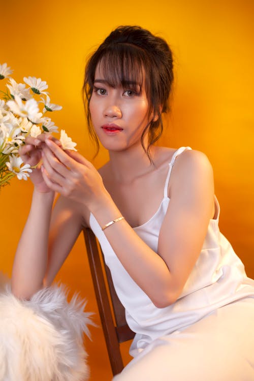 Woman in White Tank Top Holding White Flowers