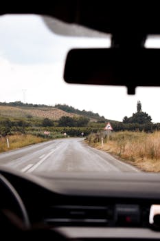 View of a hilly countryside road taken from a car dashboard, great for travel themes.