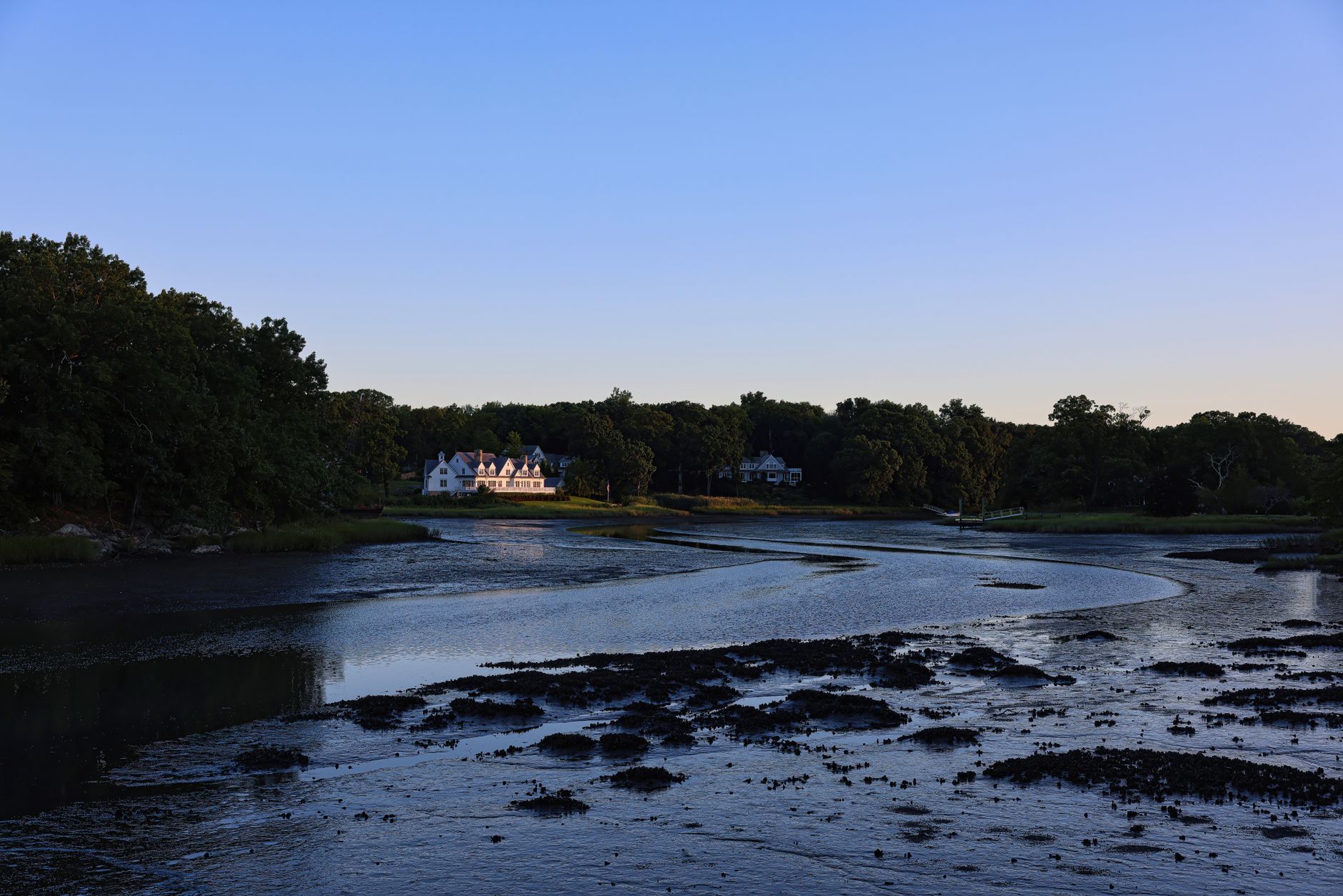Peaceful lakeside scene in Darien, CT, with a distant house at sunrise.