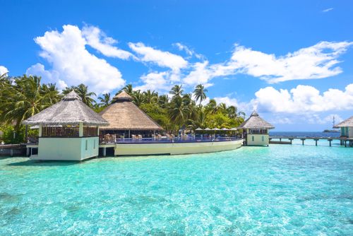 Free Stunning view of a tropical resort in the Maldives with clear turquoise waters and lush palm trees. Stock Photo