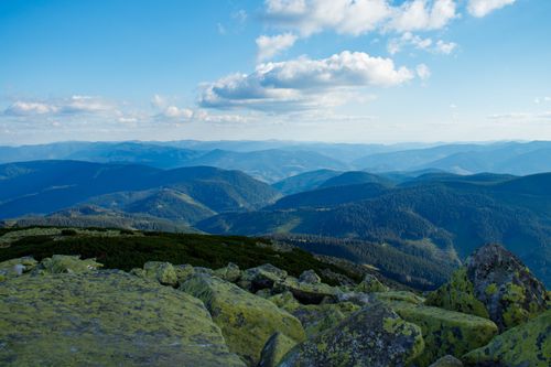 Free Breathtaking view of a mountain range with mossy boulders and blue sky. Stock Photo