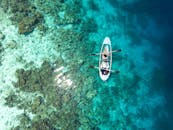 从鸟瞰图中可以清晰地看到，一艘独木舟正滑行在马尔代夫碧绿水域充满活力的珊瑚礁之上