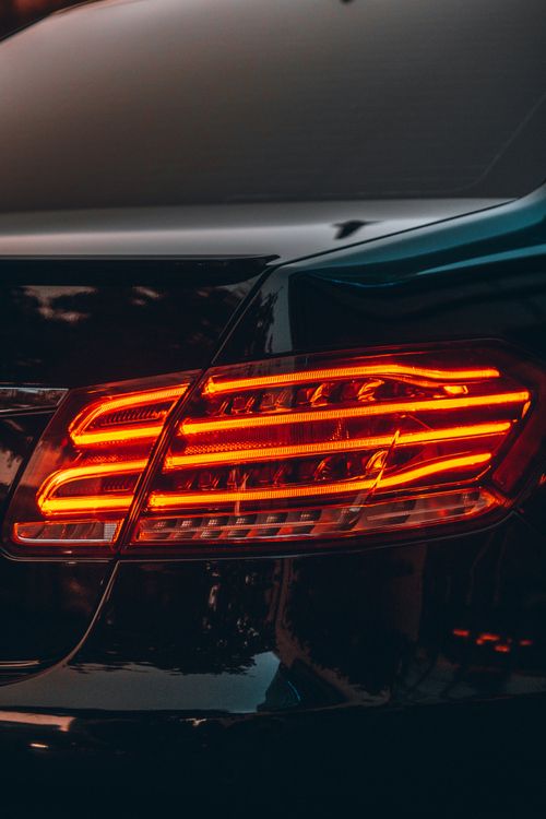 Free Vibrant orange tail lights of a shiny black car in a vertical shot at night. Stock Photo