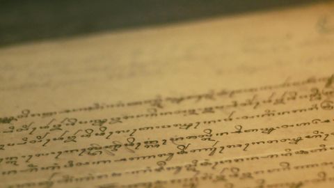 Close-up of an antique book page with cursive writing and aged paper texture.
