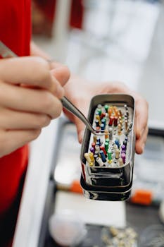 Detailed close-up of dental instruments in a sterilization box held by hand with forceps.