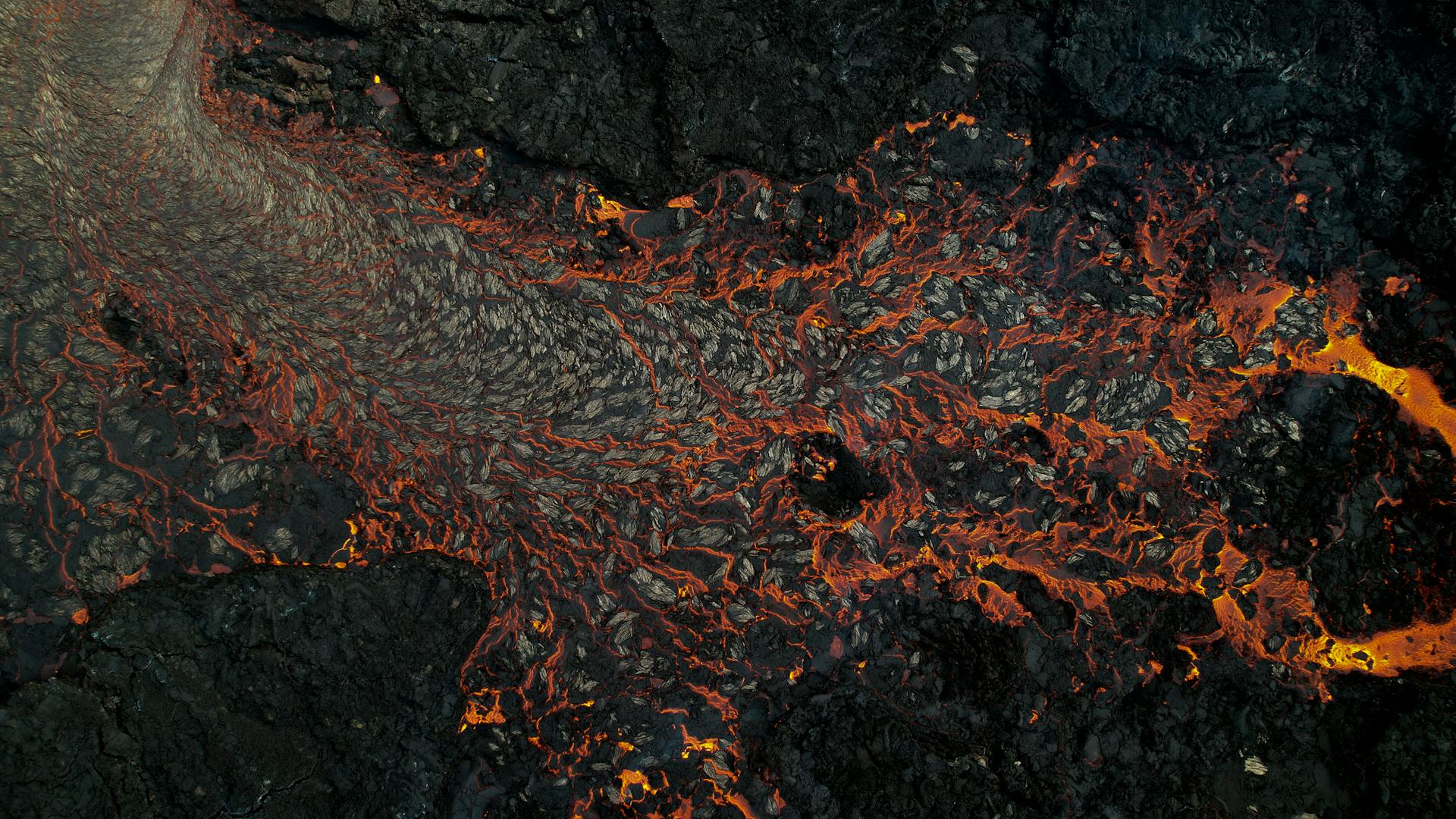 Aerial view of glowing lava flowing across volcanic terrain in Iceland
