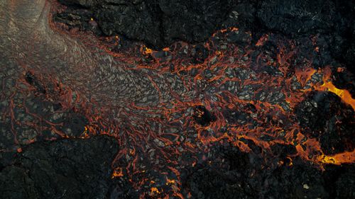 Free Stunning aerial shot of lava flowing across dark volcanic rocks in Iceland. Stock Photo
