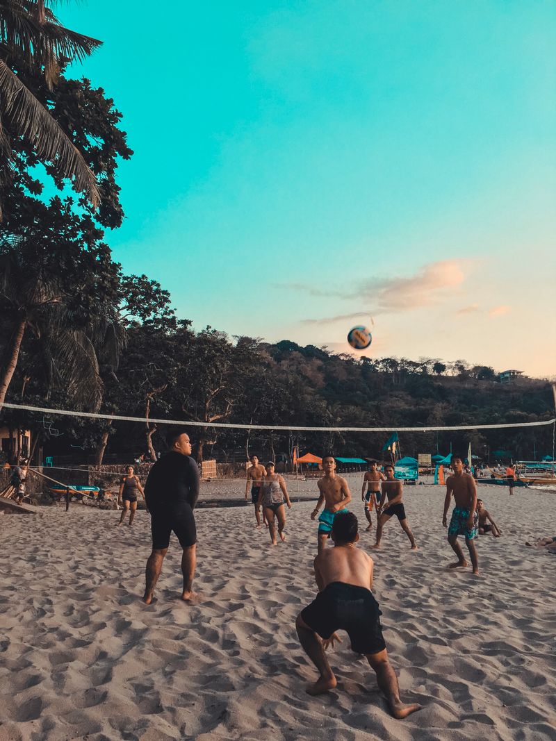 Amigos jugando voley playa al atardecer