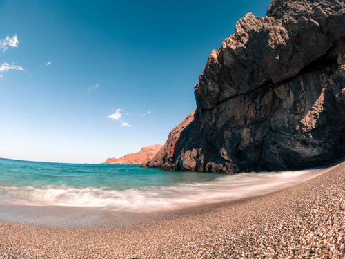 Free Beautiful beach with clear seas, rocky formations, and a bright blue sky. Stock Photo