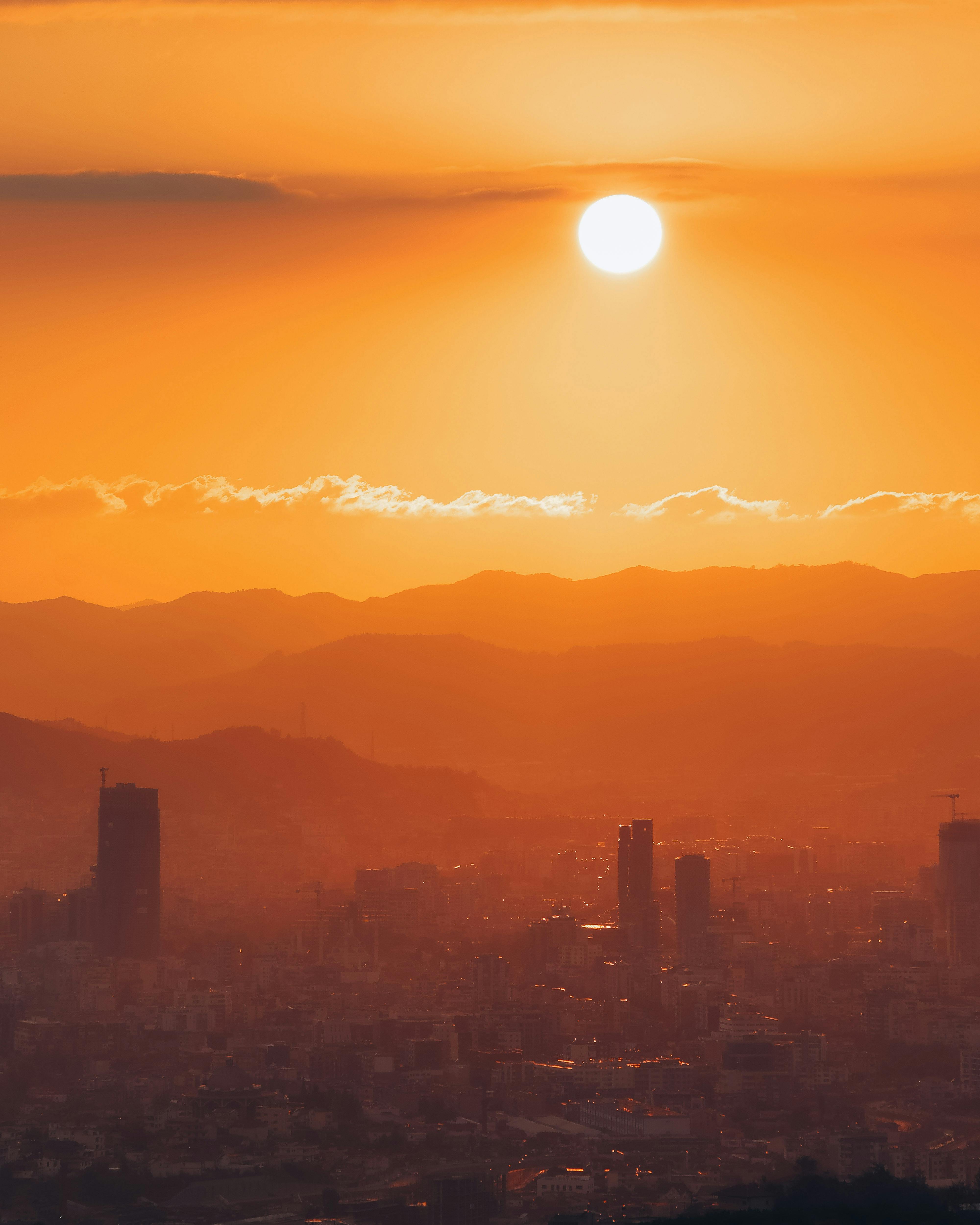 Stunning sunset view of Tirana cityscape, silhouetted against distant mountains.