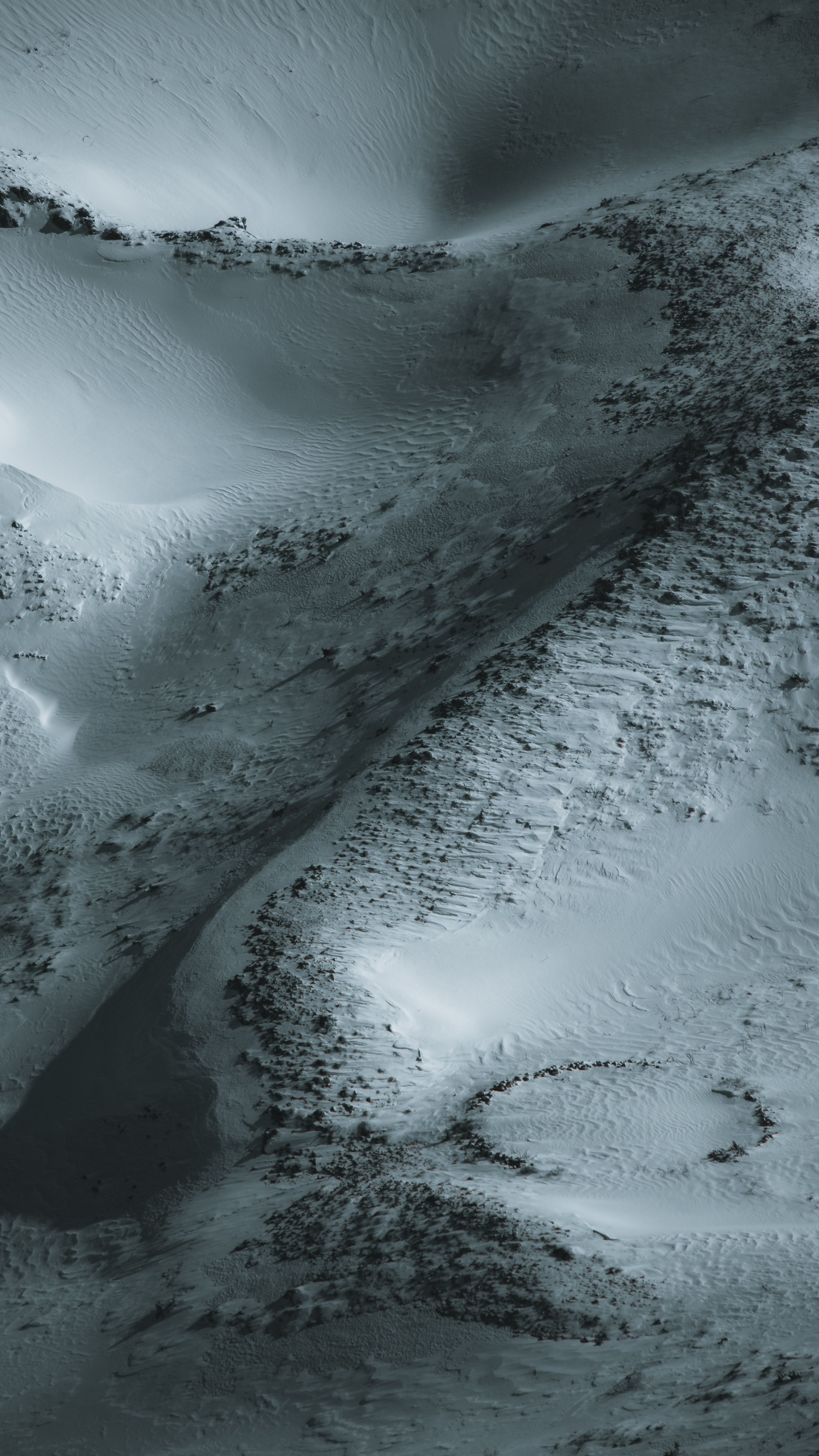 Dramatic aerial shot of a snow-covered mountain landscape during winter.