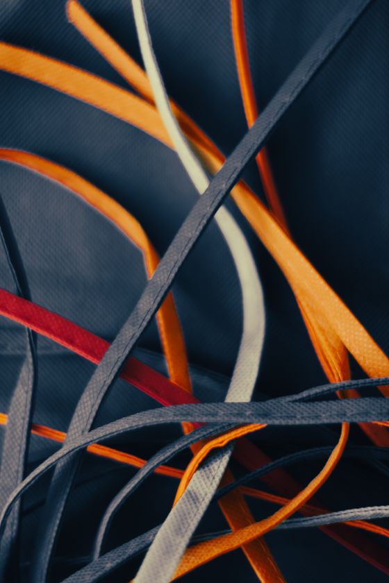 Tangled coloured shoelaces on a dark blue ground — photo by Steve A Johnson on Pexels